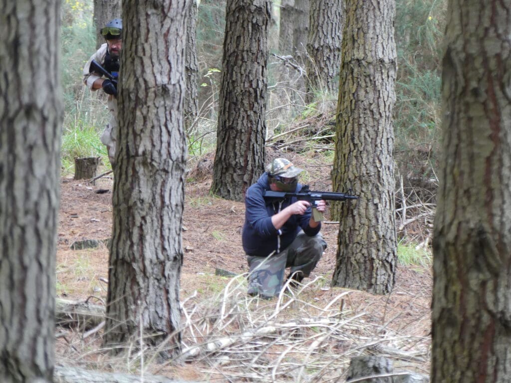 I am in the foreground kneeling behind a tree providing cover to a teammate as he runs behind to try and flank the enemy