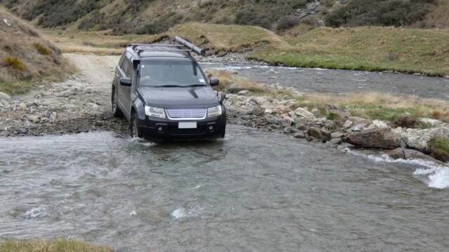 Entrying the water for the river crossing The Suzuki Escudo entering the water in a river crossing with a river and hills in the back ground
