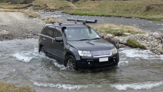 Just about out of the river crossing The Suzuki Escudo just about out of the river crossing with a river and hills in the background