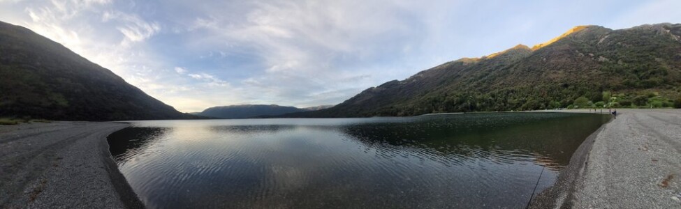 Trying for a fish on dusk Panoramic view of Loch Katrine at dusk with people fishing