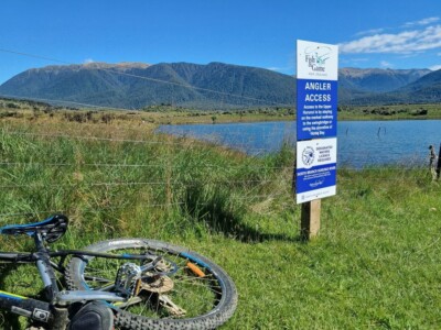 Stopped my mountain bike ride here to try for a fish as I saw a few crusing and rising in the background. The back of my mountiain bike on the ground near a Fish and Game information sign with the top of Loch Katrine in the background